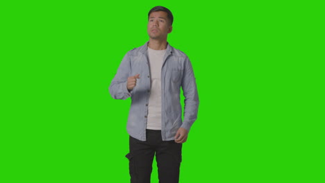 studio shot of casually dressed stressed young man against green screen