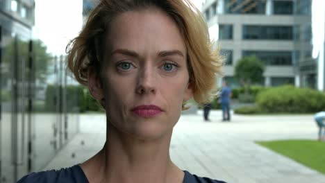 portrait of confident businesswoman standing outside office buildings staring to camera