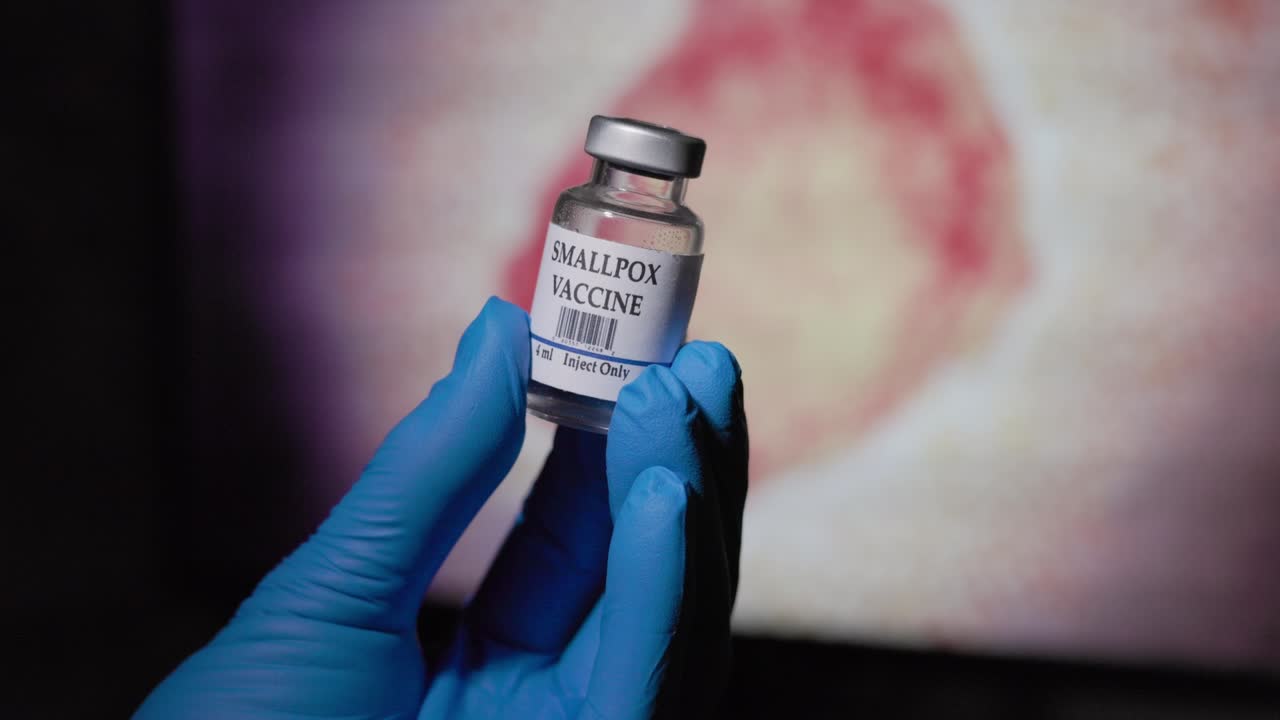 doctor holding a vial of smallpox vaccine in front of the monkeypox virus
