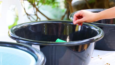 person disposes cup in outdoor trash bin