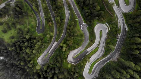 sobrevuelo aéreo con vista de pájaro de los giros del paso de maloja en engadin, suiza con autos que suben y bajan por la carretera rodeada de árboles