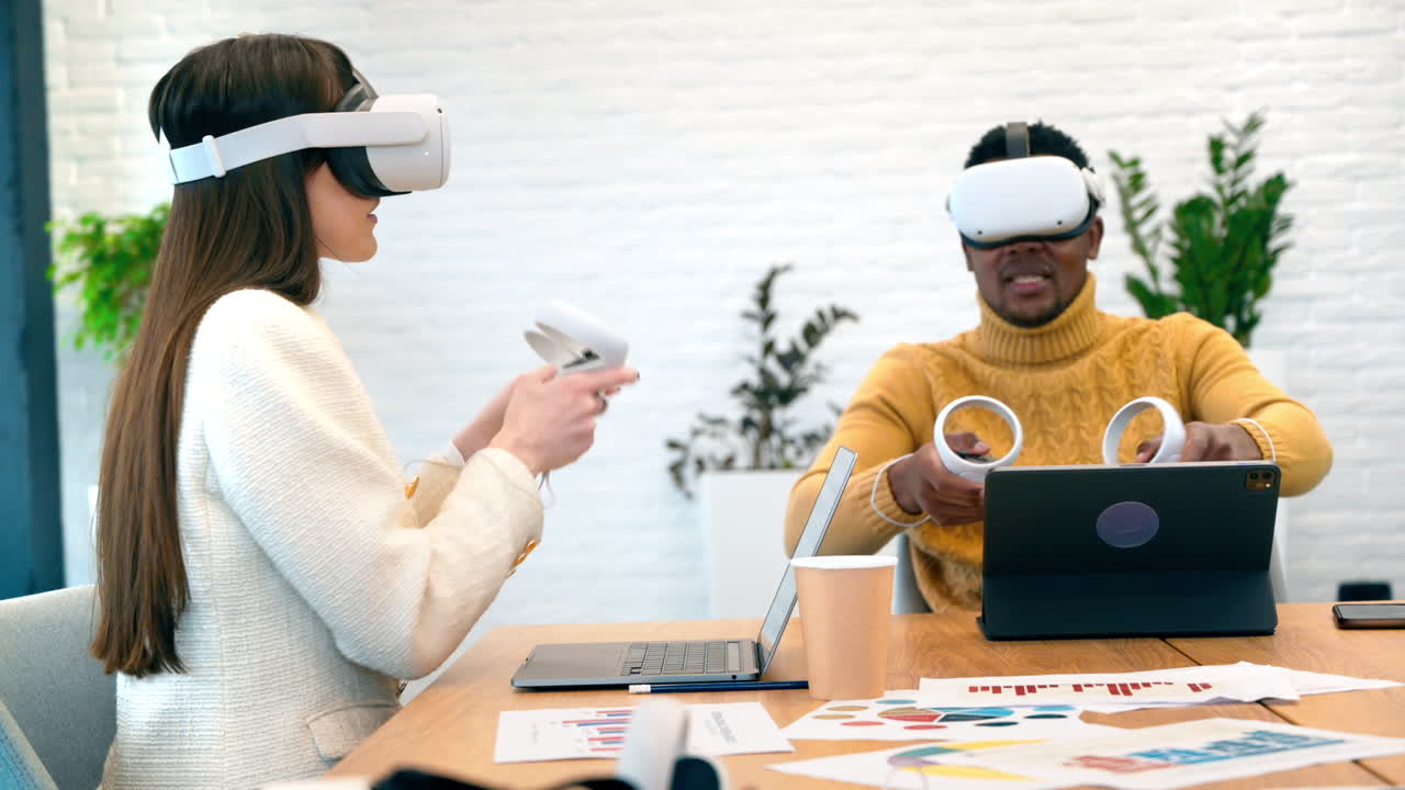 Business conference in VR in an office. A black man and caucasian woman using VR glasses and controllers, papers and gadgets on the table