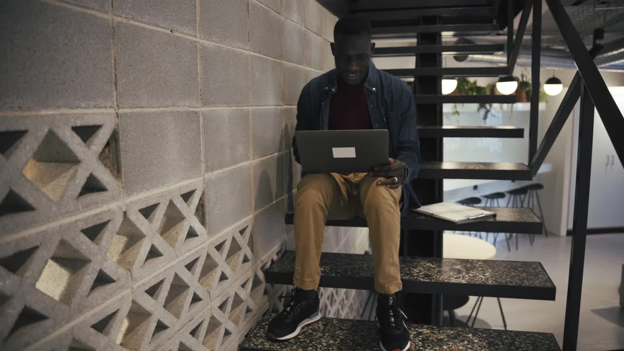 Man with laptop on stairs in office