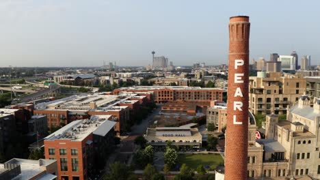 san antonio pearl district aerial orbit of brick pearl tower, pan right showing historic warehouse district buildings in 4k