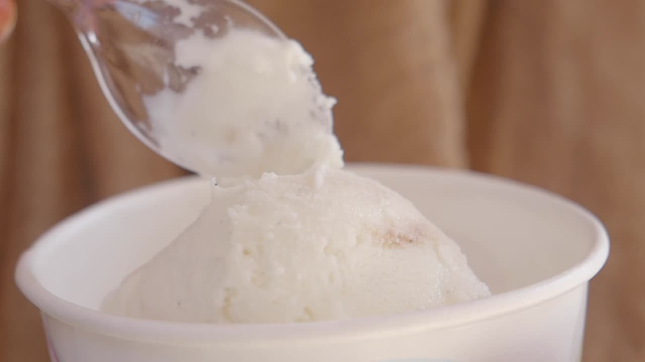 una cuchara de helado de vainilla en una taza blanca