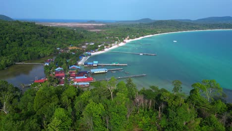 koh rong island, cambodia, showcasing a fishing village with traditional houses on stilts, turquoise water, and lush vegetation. tremendous aerial view flight overflight flyover drone