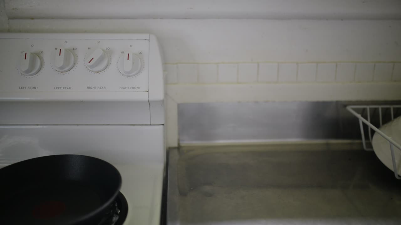 전기 스토브를 켜고 작은 프라이팬을 얹는 손