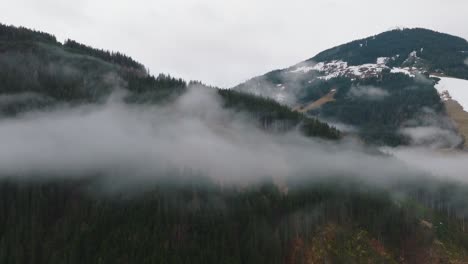 Nebelige-Wolken-Umhüllen-Die-Schneebedeckten-Gipfel-Von-Saalbach-Hinterglemm,-Luftaufnahme