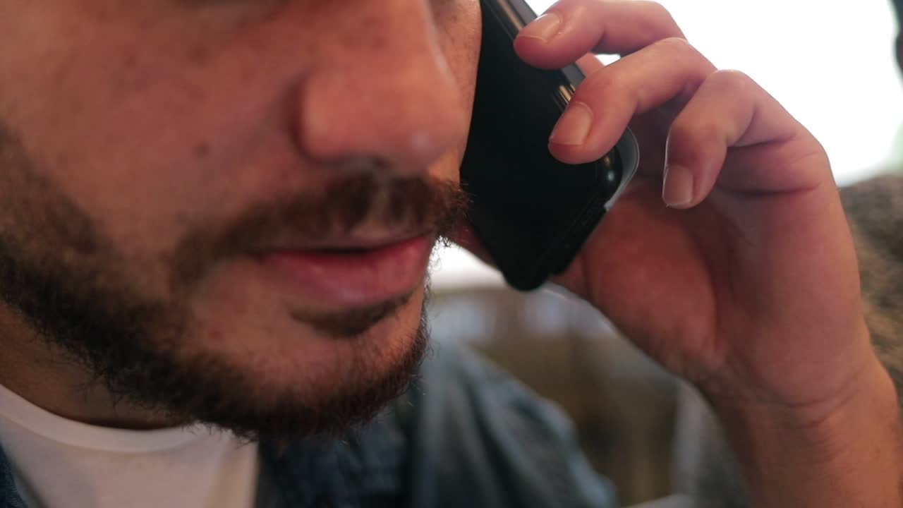 hombre barbudo hablando en serio por teléfono inteligente