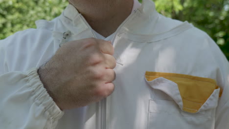 beekeeper zipping up protective suit outdoors