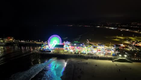 establishing aerial shot of famous santa monica pier at night of rides, ferris wheel and roller coaster