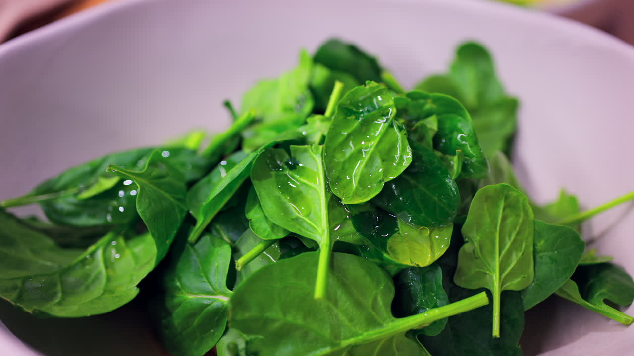 Close up of spinach leaves with oil on top on a white plate