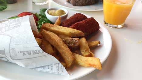 Teller-Mit-Krabbenkroketten-Und-Pommes-Mit-Einem-Glas-Orangensaft-An-Der-Seite