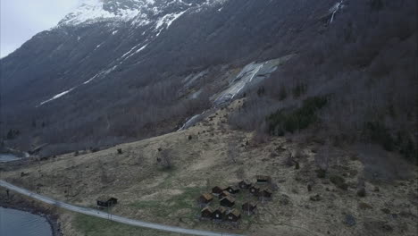 Descending-aerial-shot-of-small-village-in-Norwegian-wilderness,-rooftops-covered-by-moss,-Cloudy