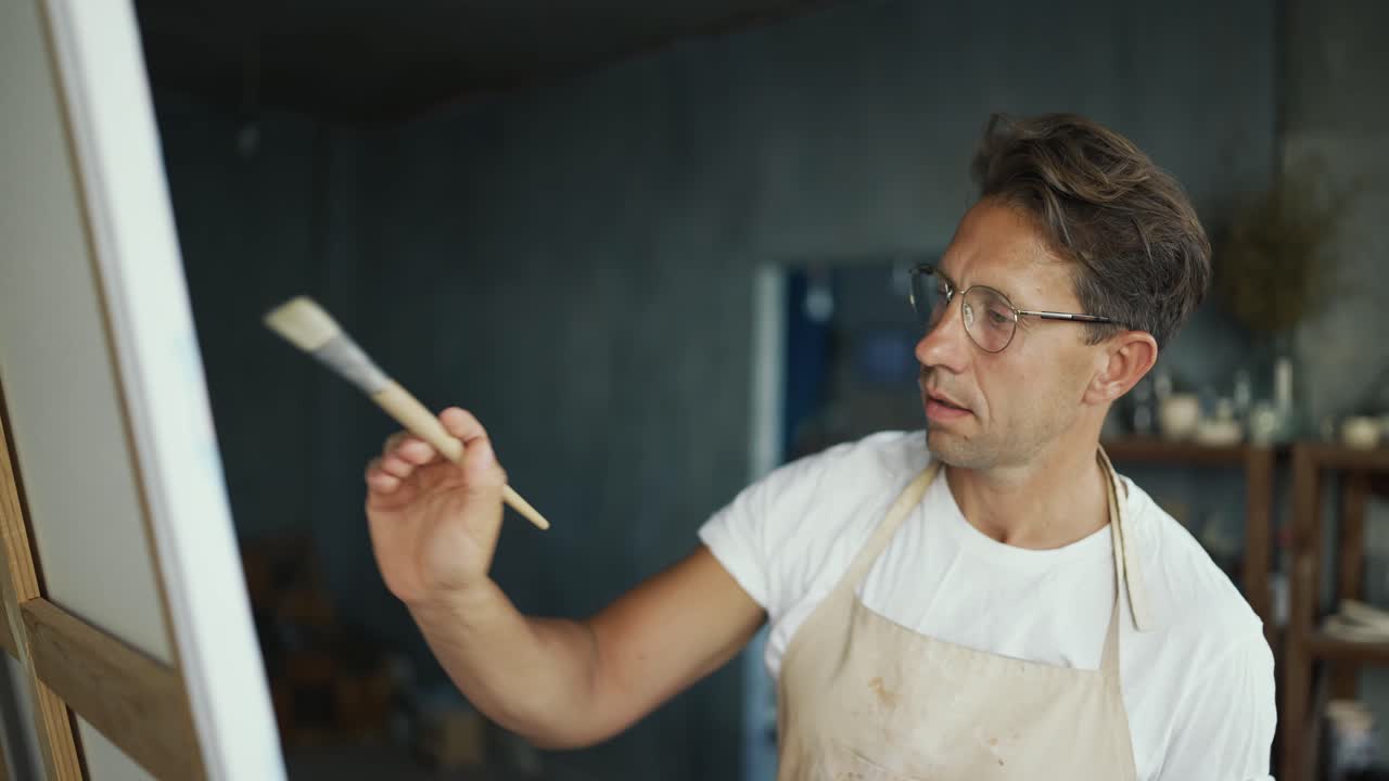 joven artista feliz con gafas dibuja en el lienzo. la vida cotidiana de una persona creativa. concepto de creatividad