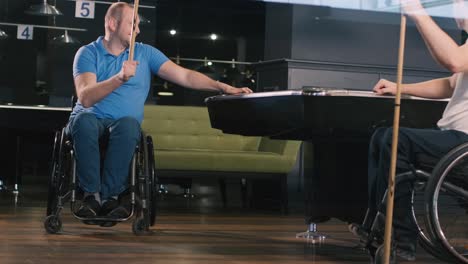 adult men with disabilities in a wheelchair play billiards in the club