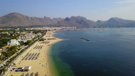 Eine-Sich-Nähernde-Drohnenaufnahme-Zeigt-Den-Gesamten-Abschnitt-Des-Playa-Del-Port-De-Pollenca,-Einem-Beliebten-Touristenziel-Auf-Der-Spanischen-Insel-Mallorca.