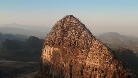 Aerial-shot-of-a-huge-mountain,-lit-up-but-the-sunset-sun