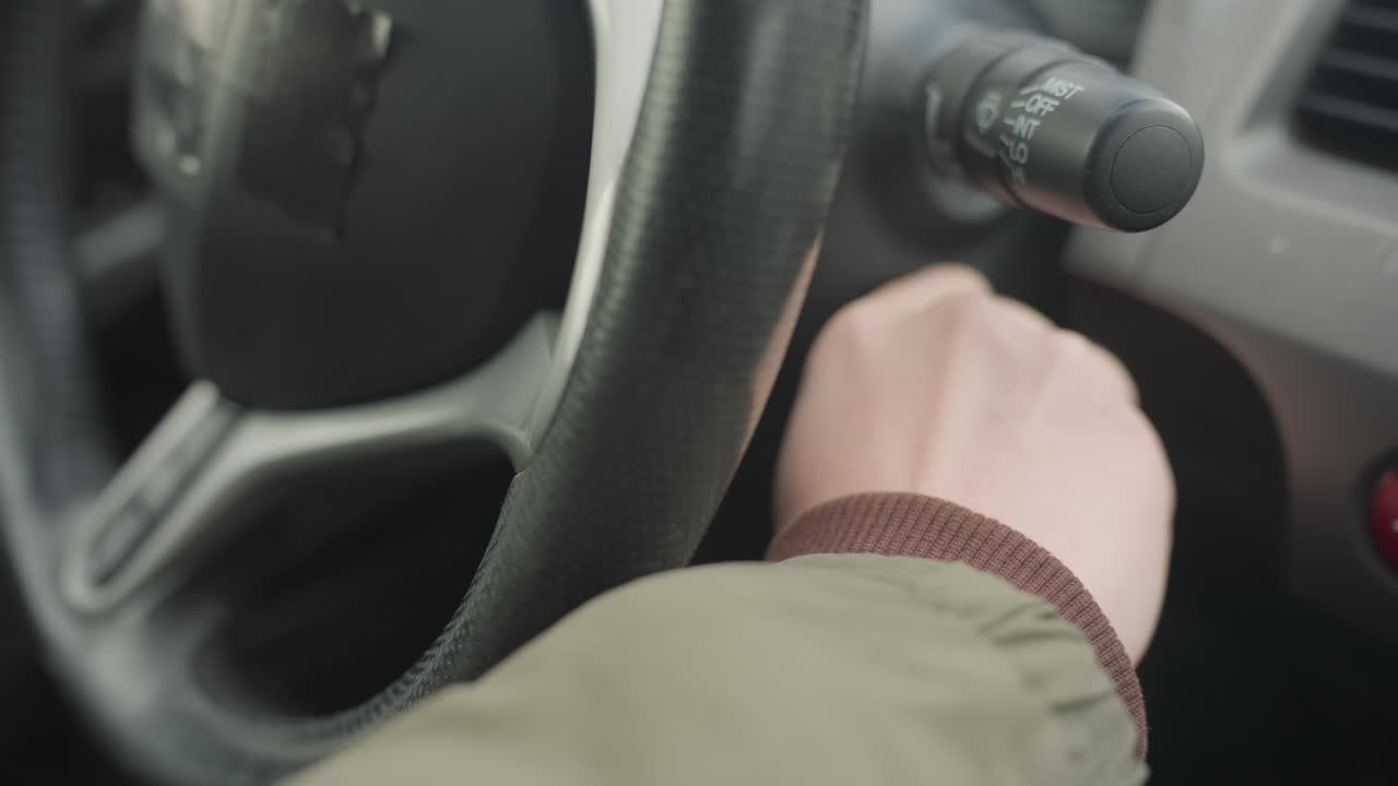 close up of driver wearing winter jacket inserting key into car ignition near steering wheel, capturing moment of preparation before starting engine inside modern vehicle with cold weather outside