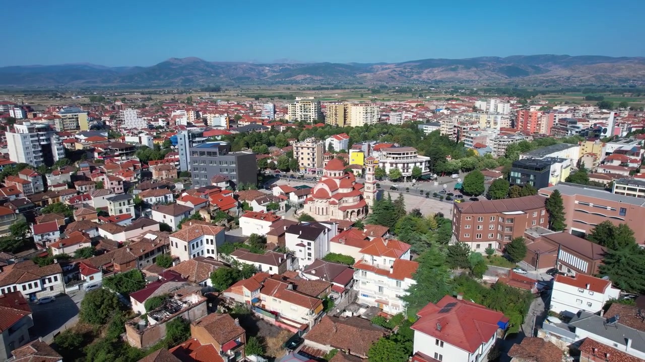 Sole mattutino su una tranquilla passeggiata pedonale nel centro di Korça con edifici e case tradizionali.