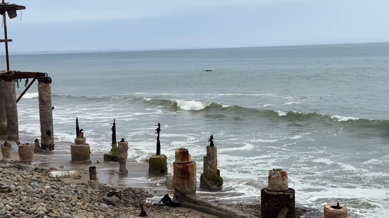 Handheld wide panning shot of a beachfront home burned by the Palisades Fire along Pacific Coast Highway in Malibu, California. 4K