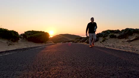 a person walks along a coastal road at sunset, capturing serene landscapes and warm lighting