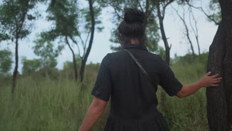 Mujer-Joven-Caminando-Por-Un-Campo-De-Hierba-Con-árboles