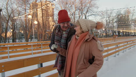 happy elderly couple ice skating