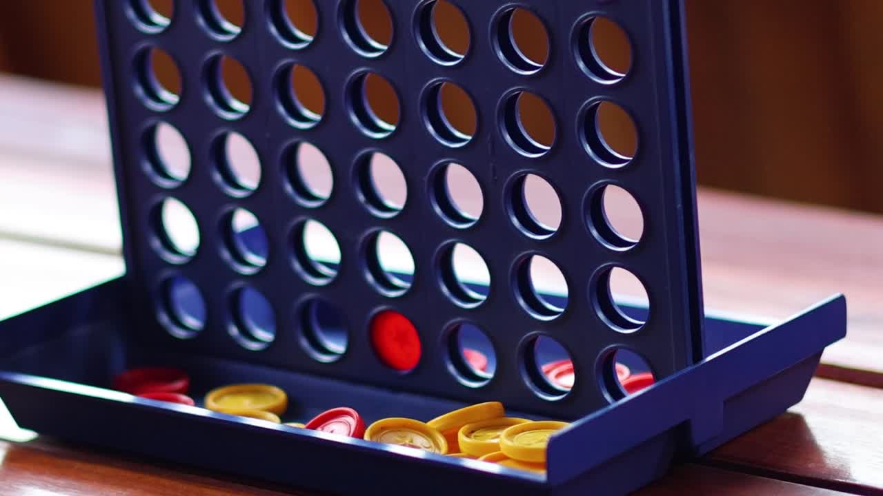 A detailed view of red and yellow discs in a Connect Four game on a wooden table.