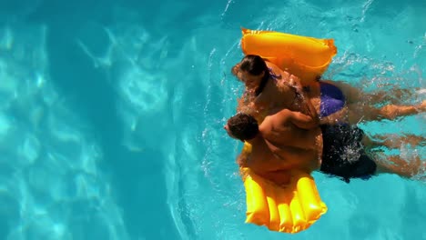 Couple-swimming-on-lilo-in-pool-together