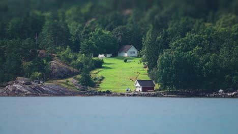 a cottage and a boathouse on the shore of the hardanger fjord