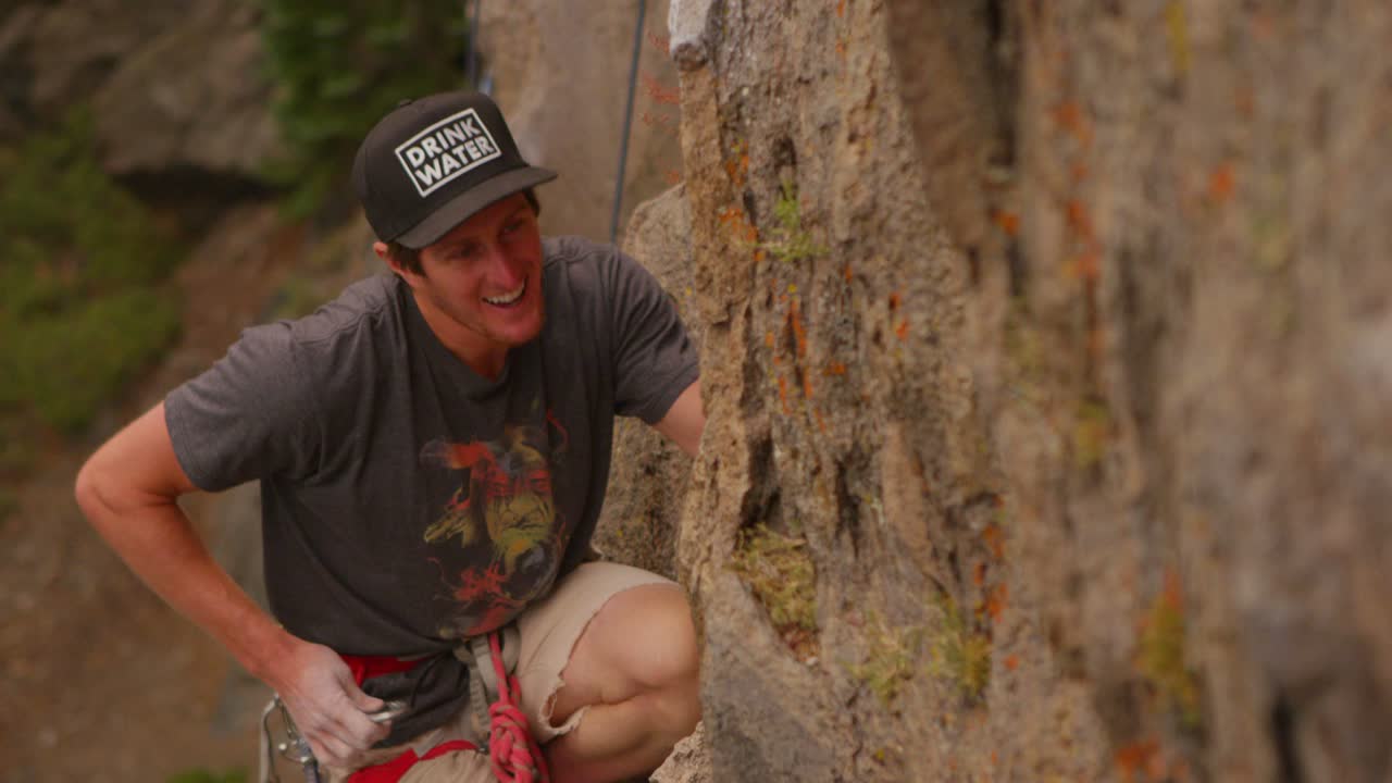 un escalador coloca un mosquetón mientras escala una pared de roca