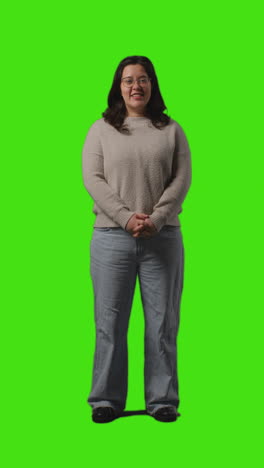 Vertical-Video-Full-Length-Portrait-Shot-Of-Smiling-Casually-Dressed-Young-Woman-Standing-Against-Green-Screen