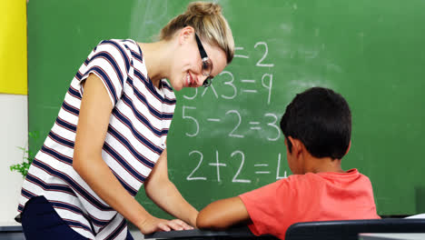 Teacher-helping-schoolboy-with-their-studies-in-classroom