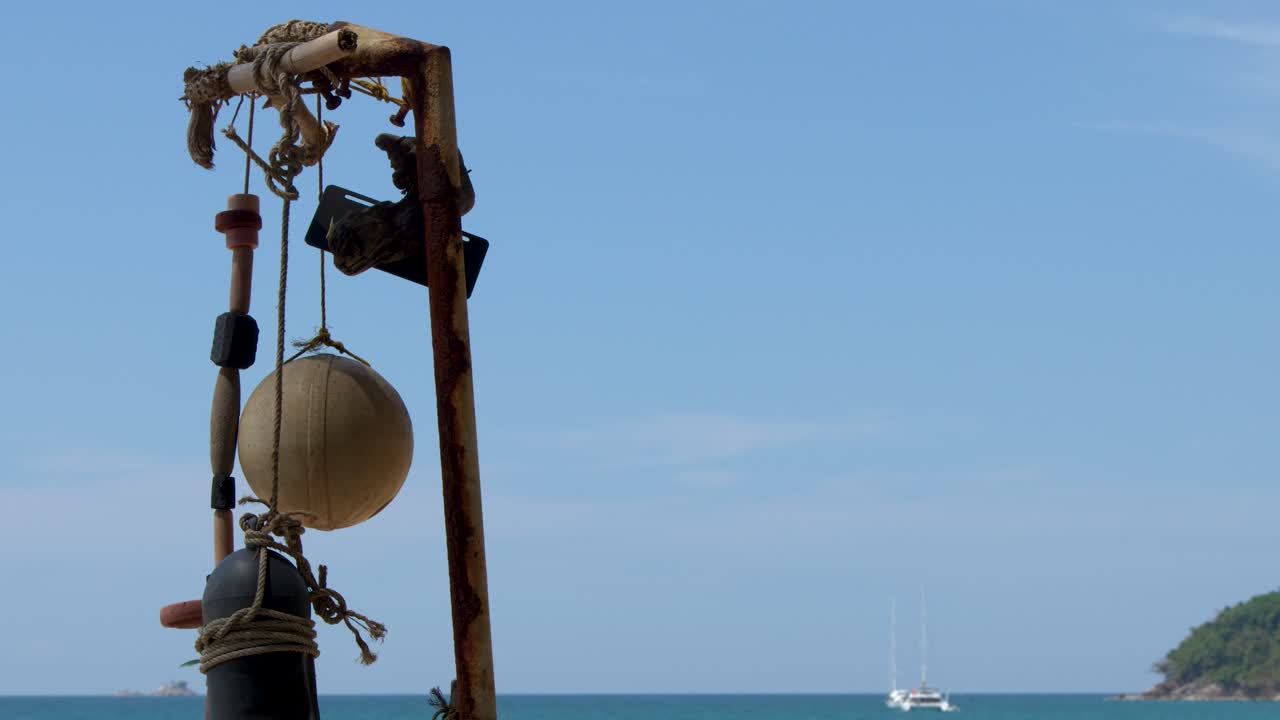 Ripresa statica di una spiaggia tropicale con boe, barche a vela e bagnanti, in pieno giorno.