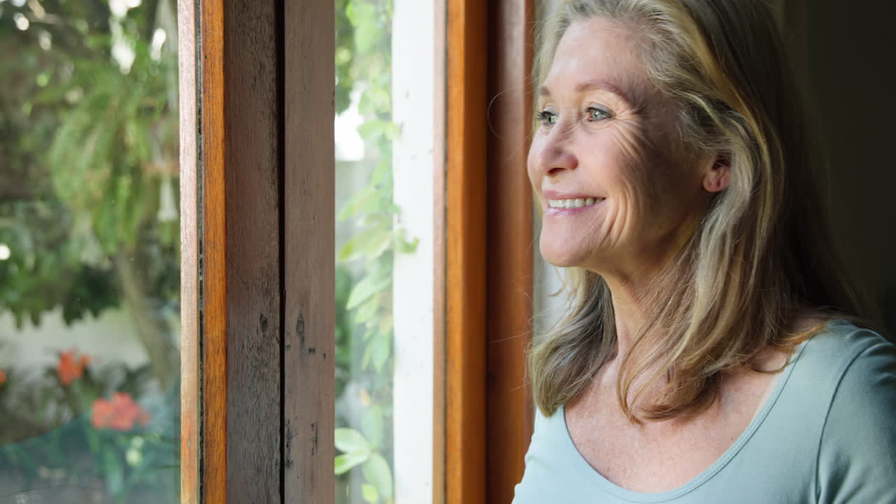Smiling senior woman enjoying morning coffee by window at home