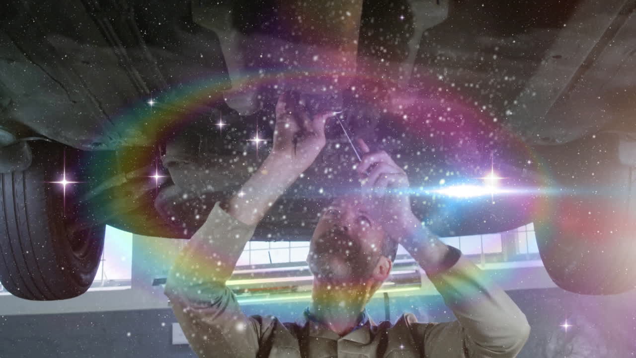 Male mechanic tightening car part beneath lift in auto garage, featuring lens flares and sparkles