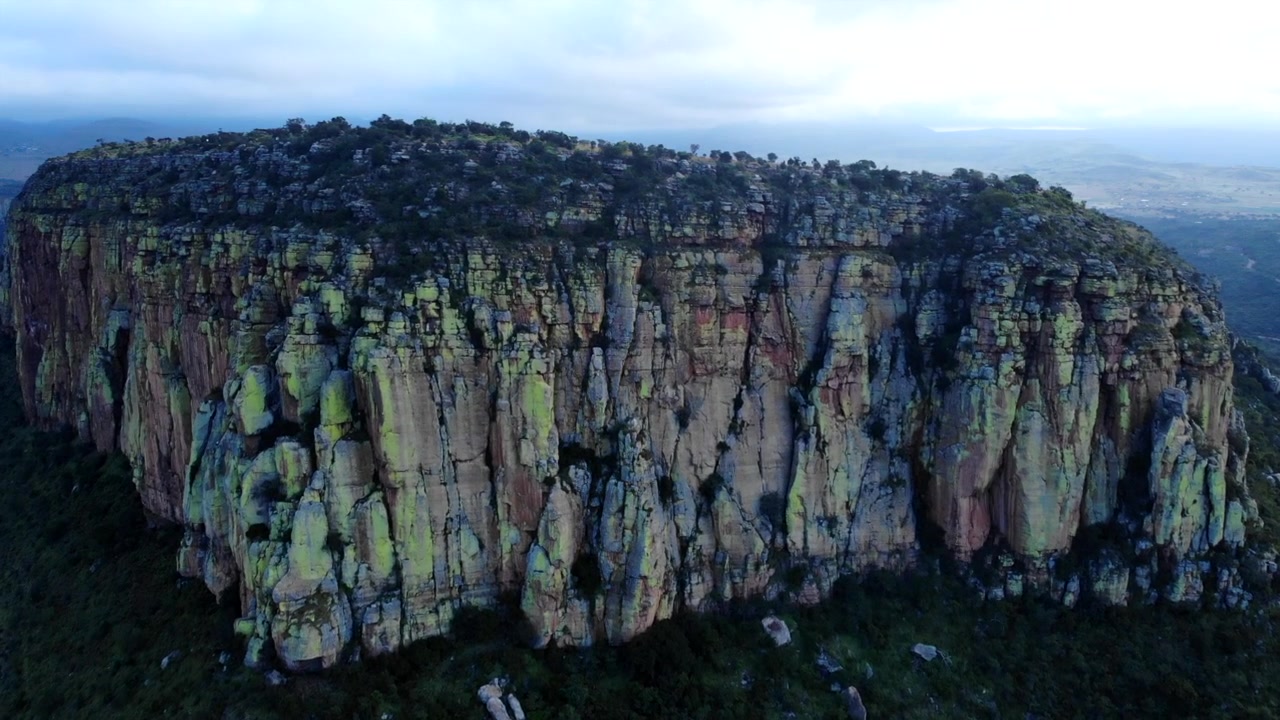 Mesa cubierta de musgo vista aérea al anochecer, amplio panorama cinematográfico de una meseta con líquenes verticales.
