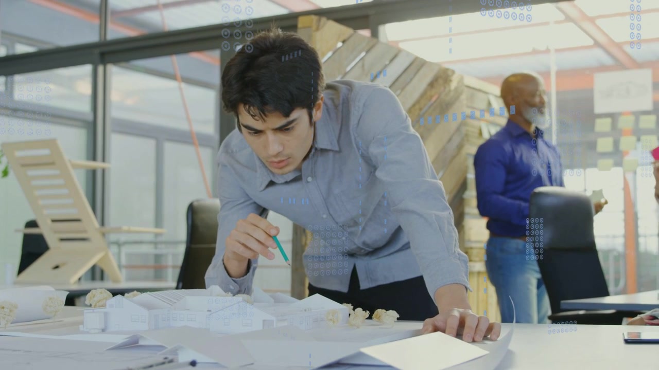 Designer leaning at desk, pencil hovering, marking design model, causing glass overlay for review