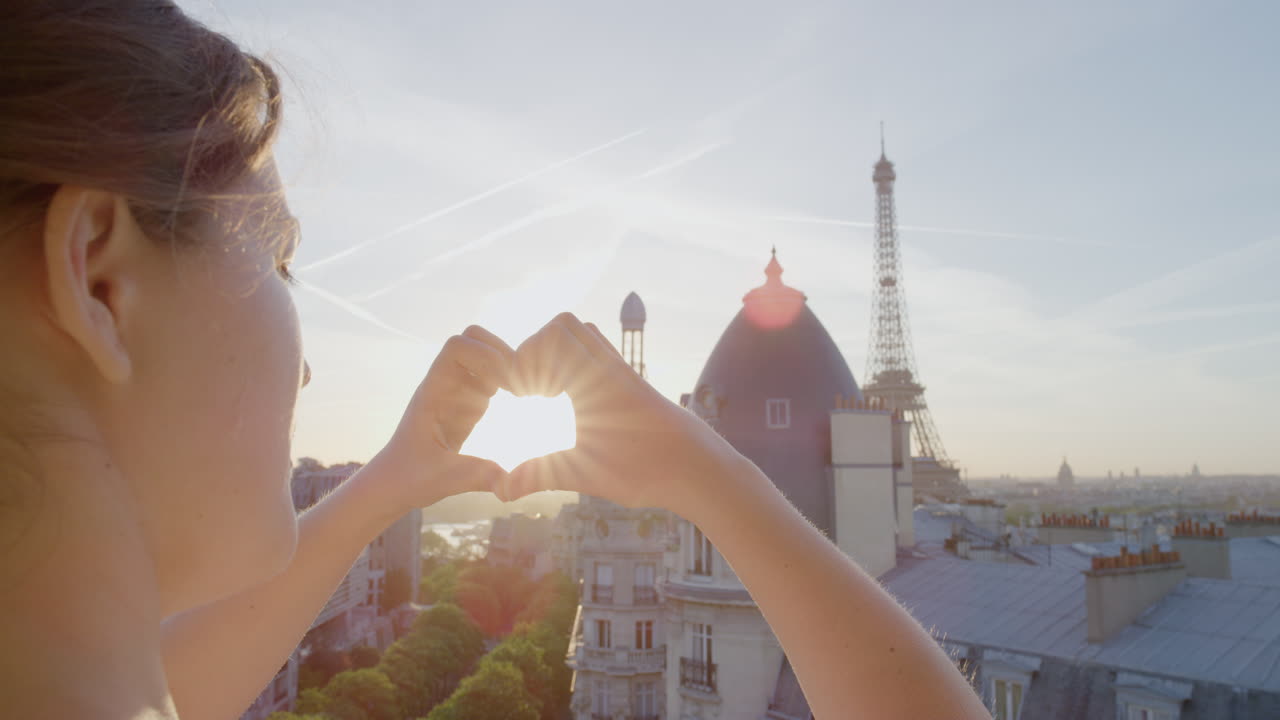 mani di giovane donna che fanno forma di cuore gesto tenendo il sole fiamma godendo vacanza di viaggio romantico a parigi francia guardando la bellissima torre eiffel