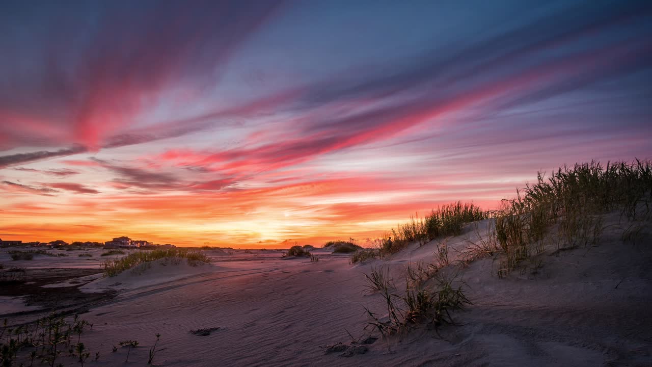lapso de tiempo de dunas de arena, una playa, algunos autos, nubes y un colorido amanecer