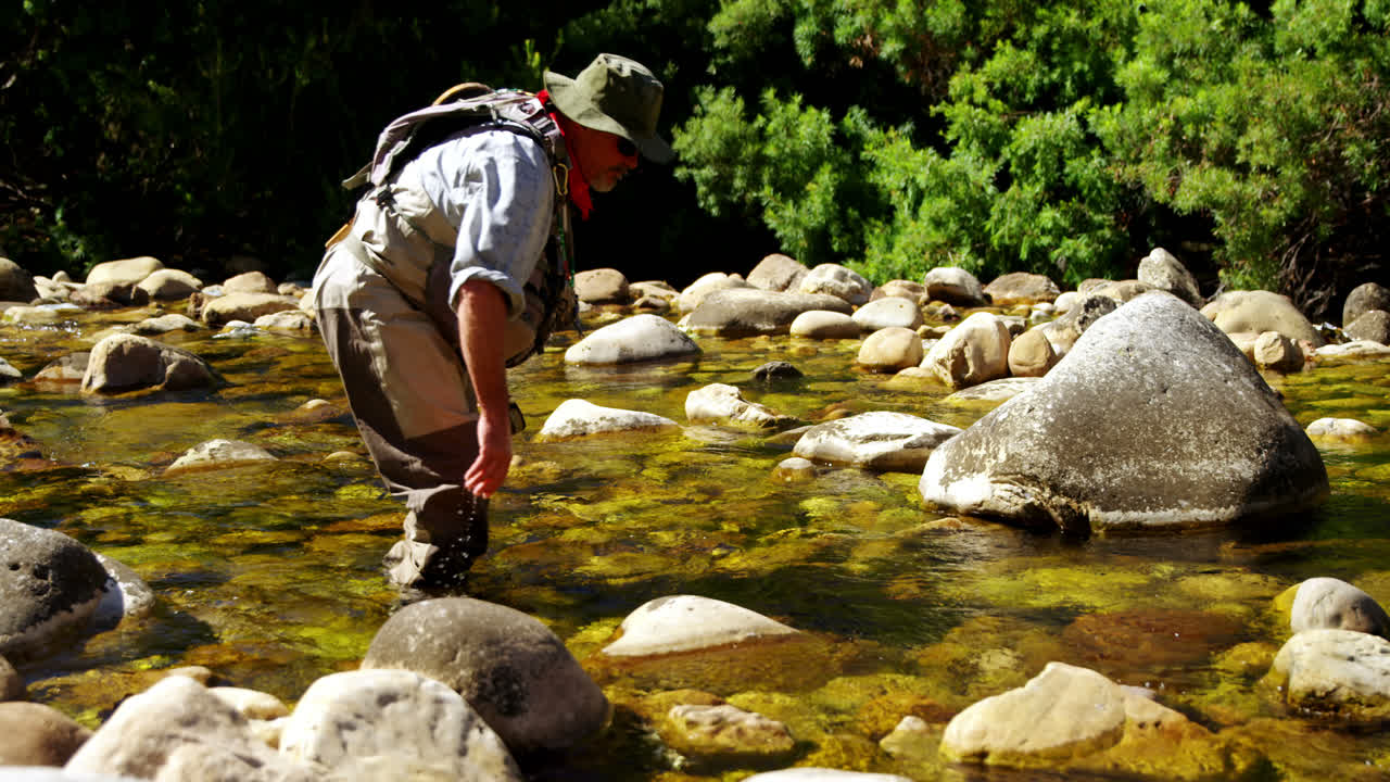 pescador con mosca en busca de peces en aguas poco profundas del río