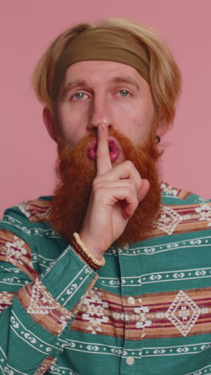 Young man presses index finger to lips makes silence gesture sign do not tells secret shh be quiet