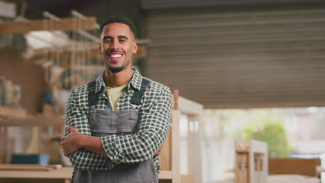 Portrait-Of-Smiling-Male-Apprentice-Working-As-Carpenter-In-Furniture-Workshop