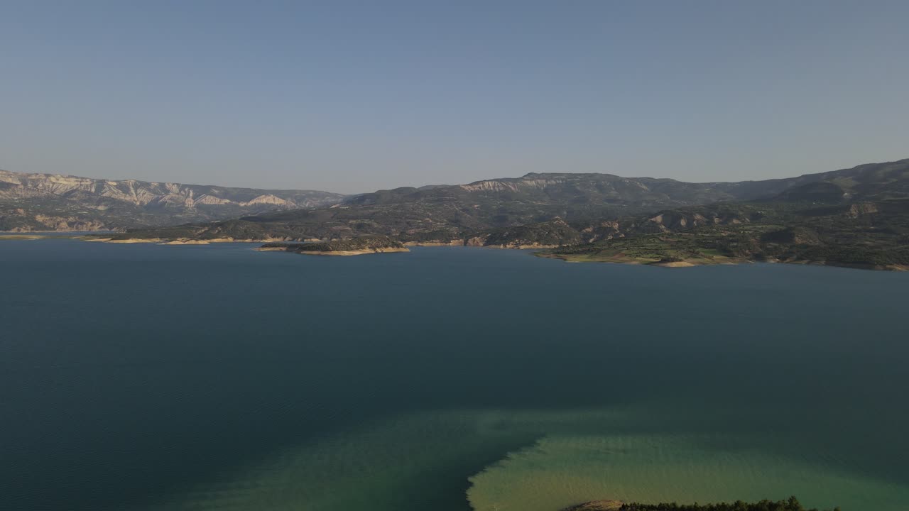 Aerial drone view of the lake in the forest, rain clouds covering the sky, overhead view of natural landscape
