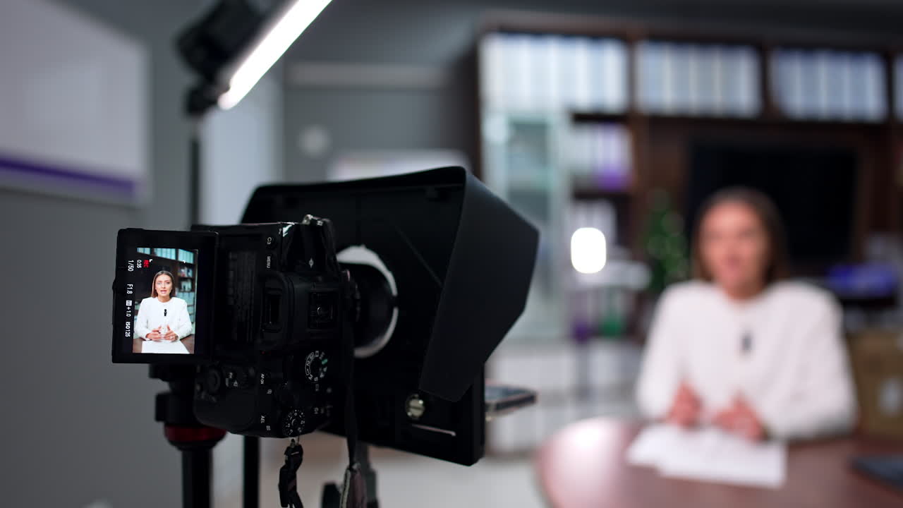 Recording a speech on professional camera. Female Caucasian blogger talks and gestures with her hands. Blurred backdrop.