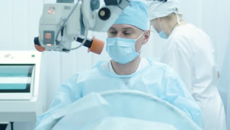 surgeon looking into the microscope at the eye of female patient at the operating room. doctor using microscope during eye surgery process, treatment of cataract and diopter correction.