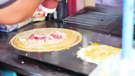 making thai pancake with toppings on a griddle