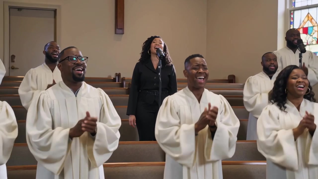 Starting lead singer in black leading worship at mic in church, robed choir clapping and singing