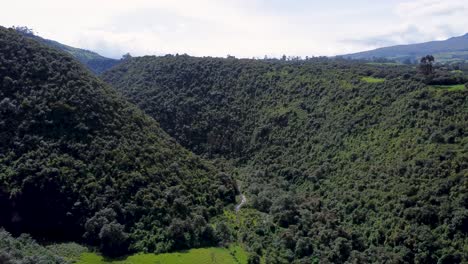 Epic-drone-clip-taking-off-over-a-large-lush-green-canyon-in-Puichig,-Equador